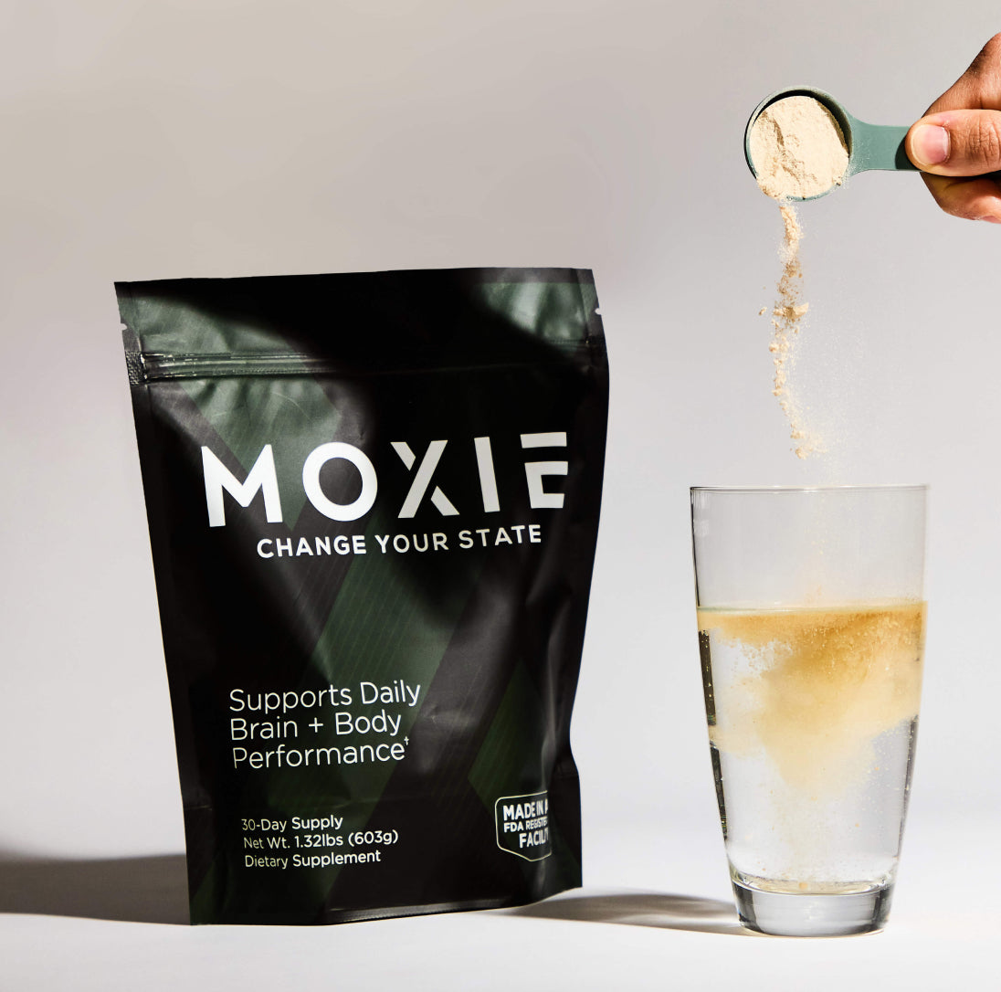 Photo of Moxie packaging next to a hand pouring a scoop of supplement into a glass of water. Creatine for focus, energy, and strength.